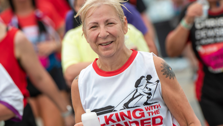A female participant takes part in a fundraising run. She looks at the camera with a smile.