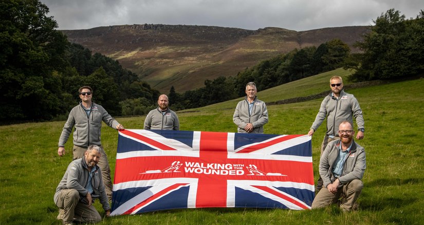 The team on the Grenadier Walk of Oman, reimagined in the UK, holding a WWTW flag